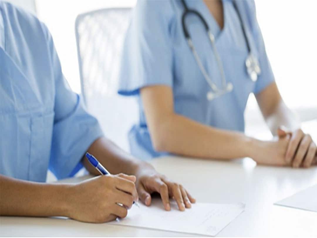 Nurses at a desk with pen and paper.